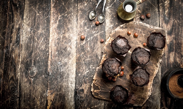 Schokoladenmuffins mit heißem Kaffee auf Holztisch.