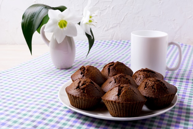 Schokoladenmuffins und Kaffeetasse auf der karierten Serviette