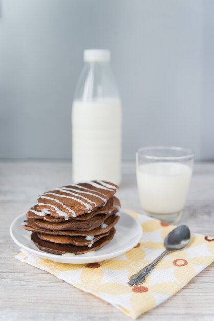 Schokoladenpfannkuchen mit Glas und Flasche Milch