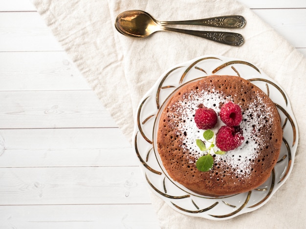 Schokoladenpfannkuchen mit Puderzuckerhimbeere auf hellem Hintergrund