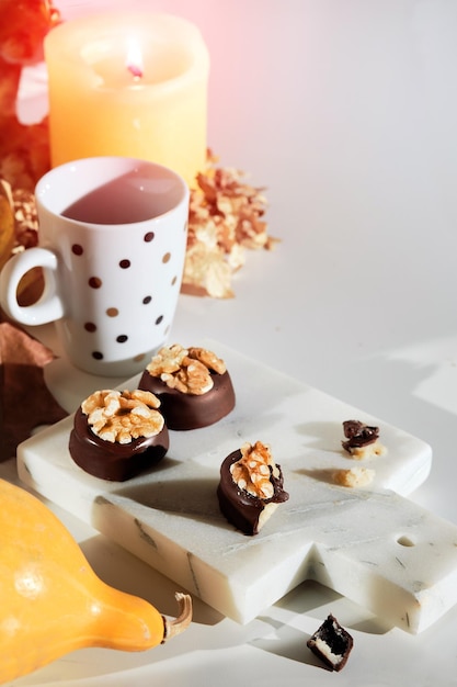 Schokoladenpralinen mit Walnussnüssen auf Marmor-Schneidebrett, Nahaufnahme auf Süßigkeiten-Herbst-Arrangement