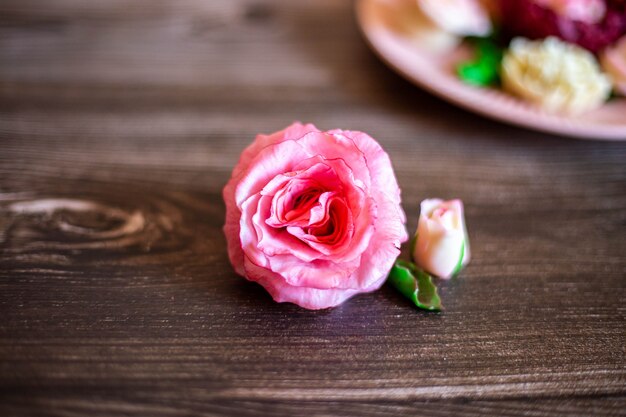 Schokoladenrosa Rose auf braunem Holzhintergrund Es gibt einen Teller mit anderen Schokoladenblumen