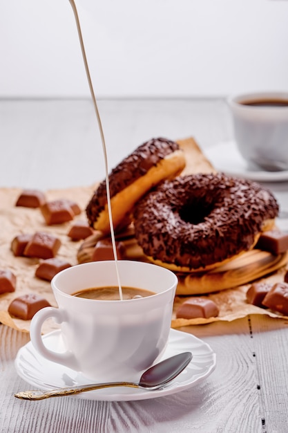 Schokoladenschaumgummiringe und Kaffee auf hellem Holz