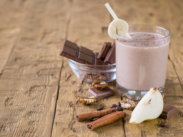 Schokoladensmoothie mit Banane und Birne auf rustikaler Tabelle der Weinlese.