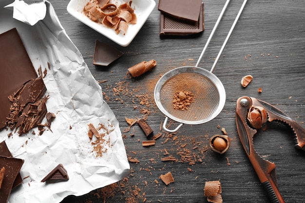 Foto schokoladenstücke mit küchenwerkzeugen auf schwarzem holztisch