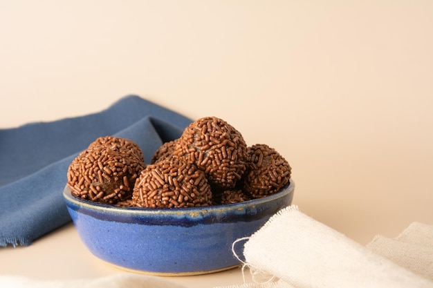 Foto schokoladentrüffelkugeln brigadeiro brasilianische süßigkeiten und schokoladenflocken frontansicht beige hintergrund