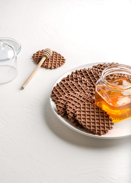 Schokoladenwaffeln mit Honig zum Frühstück auf weißem Hintergrund.