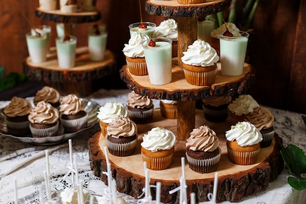 Schokoriegel auf hölzerner Hochzeitsfeier mit vielen verschiedenen Süßigkeiten Cupcakes Souffle und Kuchen