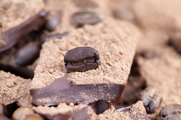 Schokoriegel mit Kakaopulver und Kaffeebohnen, Nahaufnahme von Kakaofutter, Foto mit Freizeitzutaten - Kakao und Kaffee