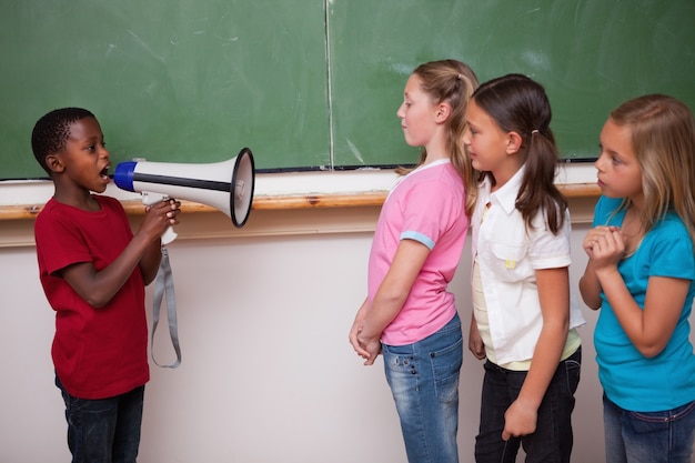 Foto schoolboy gritando através de um megafone para seus colegas de classe