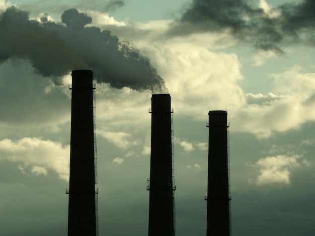 Schornsteine einer Industriefabrik verschmutzen die Luft unter dem Smog am Himmel