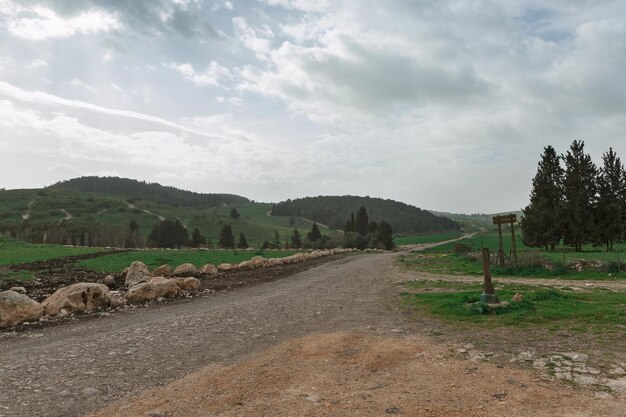 Schotterweg und grünes Feld im Hintergrund der Wolken in Israel