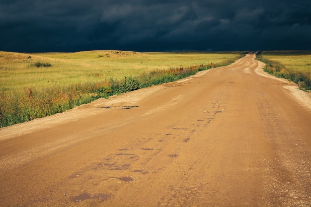 Schotterweg zur horizontlinie unter drastischen dunklen sturmwolken.