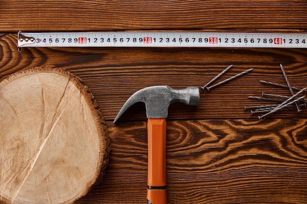 Schrauben Sie Nägel, Hammer und Maßband auf Holztisch. Professionelles Instrument, Tischlerausrüstung, Befestigungselemente, Befestigungs- und Schraubwerkzeuge