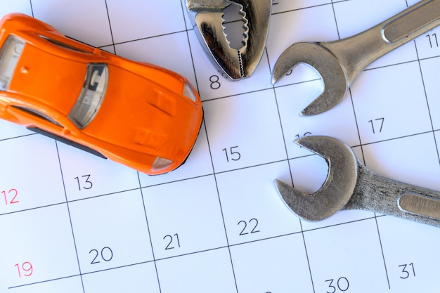 Schraubenschlüssel und Auto auf dem Kalender mit Zahlen. Reparaturkonzept