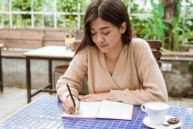 Schreiben auf ihr Notizbuch im Café