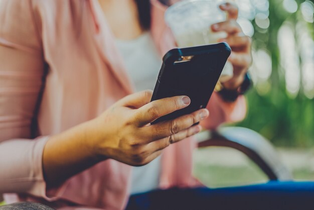 Schreibentextnachricht der Asiatin am intelligenten Telefon in einem Café.