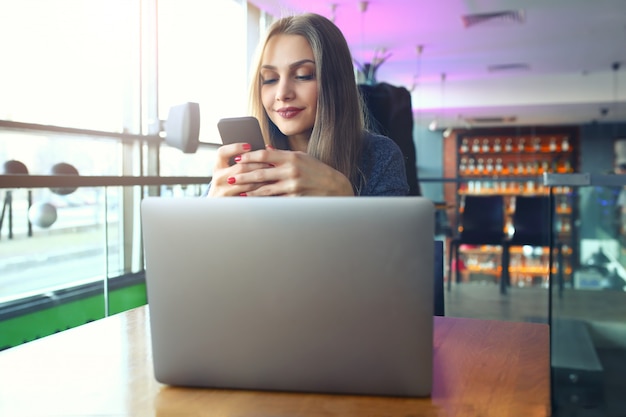 Schreibentextnachricht der Frau am intelligenten Telefon in einem Café.