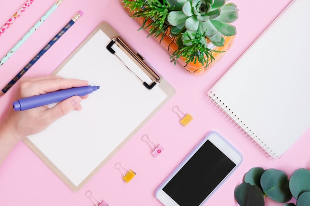 Schreibhand mit Kanzler-Flatlay auf Rosa