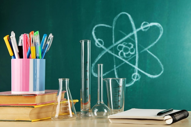 Schreibtisch im Chemieunterricht mit Reagenzgläsern auf grünem Tafelhintergrund