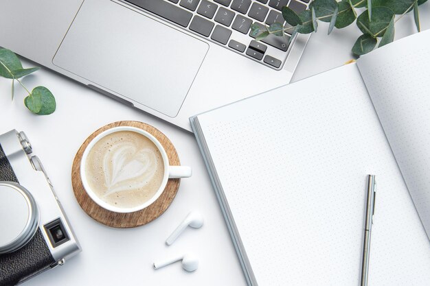 Foto schreibtisch mit laptop-kaffee-notizbuch und kamera