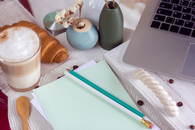 Schreibtisch mit Laptop, Kaffee und Croissant