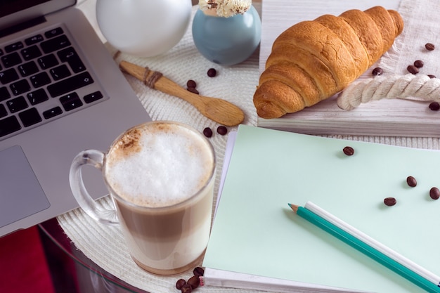 Schreibtisch mit laptop, kaffee und croissant