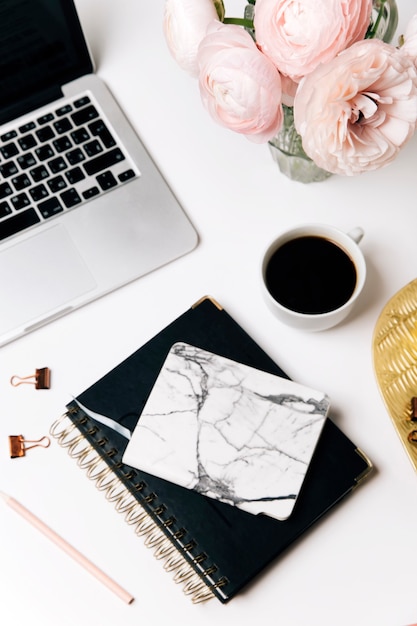 Schreibtisch mit Laptop Kaffeetasse rosa Blumen in Vase und Tagebuch auf weißem Hintergrund