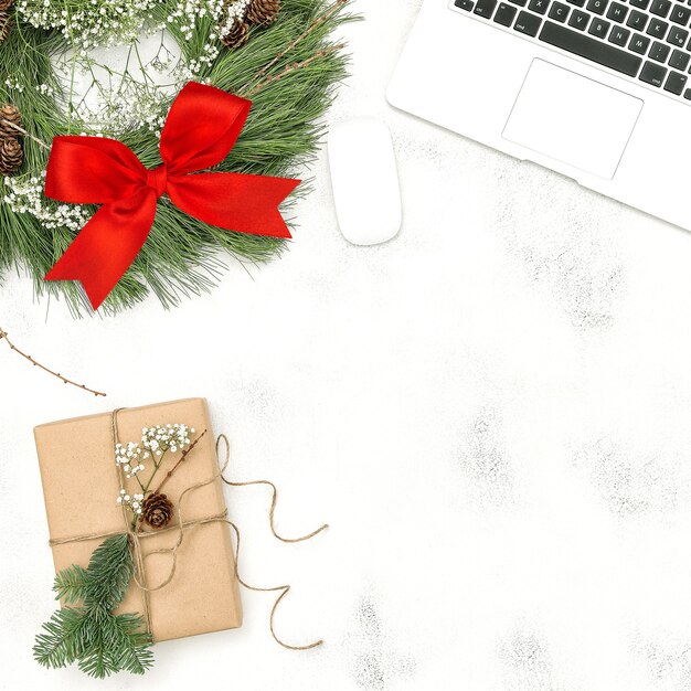 Schreibtisch mit Laptop, Weihnachtsdekorationskranz und verpacktem Geschenk. Flach legen