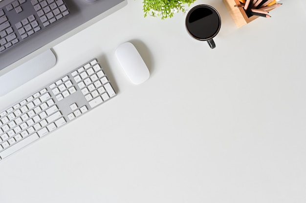 Schreibtischcomputer, -tastatur, -maus und -kaffee auf weißer Tabelle.