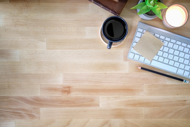 Schreibtischholztisch mit Tastaturcomputer, Tasse Kaffee und Blume. Draufsicht mit Kopienraum