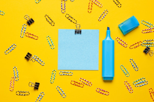 Schreibwaren Büromaterial. Büroklammer, Filzstift, Notizstück Papier auf gelbem Hintergrund