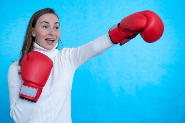schreiende starke junge Frau Boxer posiert isoliert über blaue Wand Wand tragen Boxhandschuhe.