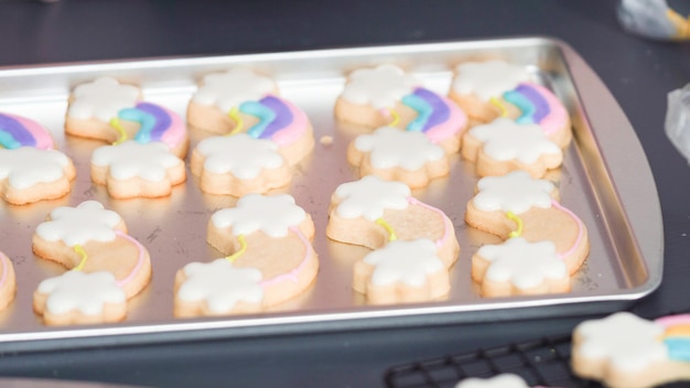 Schritt für Schritt. Dekorieren von Einhorn-Zuckerkeksen mit königlicher Glasur auf Backblech.