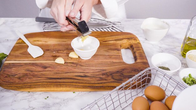 Schritt für Schritt. Den Knoblauch zerdrücken, um ihn einem Rezept für Zucchinikuchen hinzuzufügen.