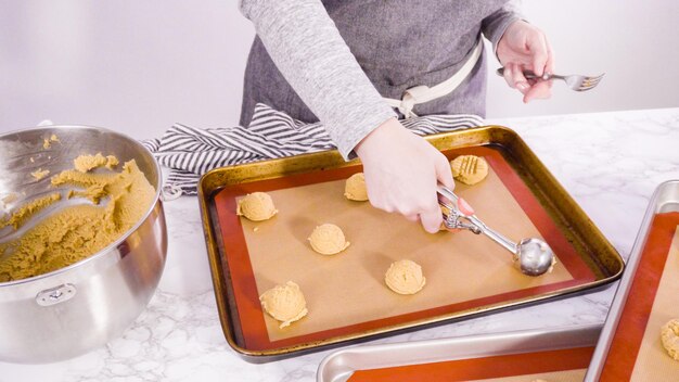 Schritt für Schritt. Erdnussbutter-Plätzchen-Teig mit Teigschaufel in das Backblech schaufeln.