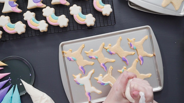 Schritt für Schritt. Flach liegen. Dekorieren von Einhorn-Zuckerkeksen mit königlicher Glasur auf Backblech.