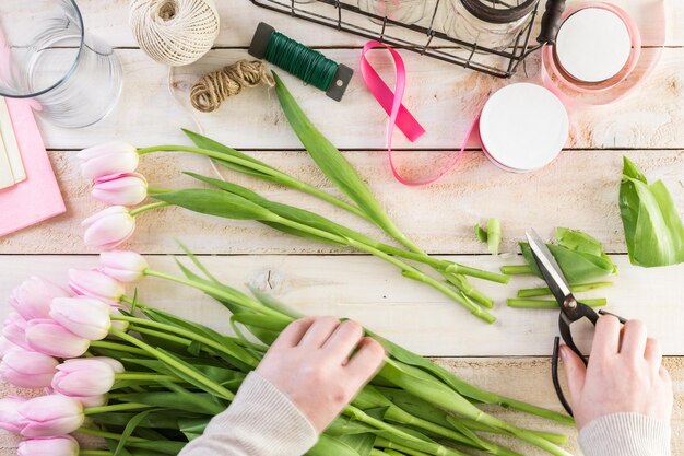 Schritt für Schritt. Florist, der rosa Tulpen in Blumenstrauß einwickelt.