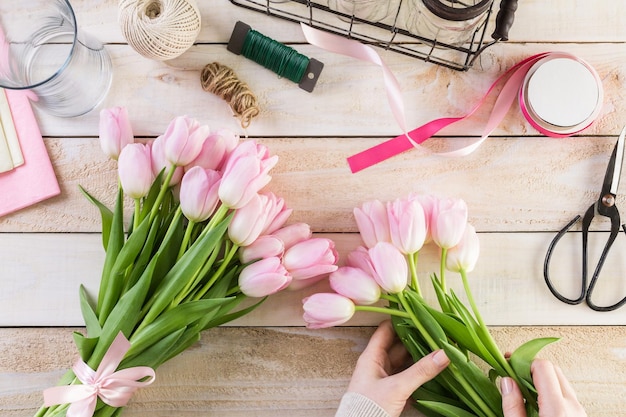 Schritt für Schritt. Florist, der rosa Tulpen in Blumenstrauß einwickelt.