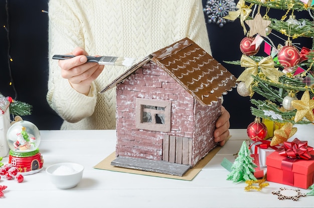 Schritt-für-Schritt-Fotoanleitung für die Herstellung eines Weihnachtsdekors ein Kartonhaus Schritt 7 Auftragen von PVA-Kleber mit einem Pinsel