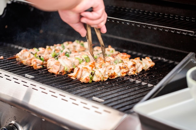 Schritt für Schritt. Grillen von Hühnchen-Yakitori auf Bambusspießen auf einem Gasgrill im Freien.