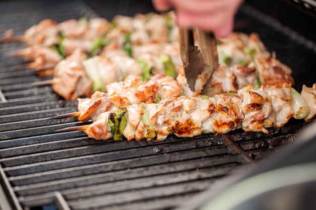 Schritt für Schritt. Grillen von Hühnchen-Yakitori auf Bambusspießen auf einem Gasgrill im Freien.