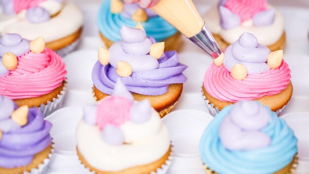 Schritt für Schritt. Konditor, der Buttercreme-Zuckerguss auf Einhorn-Cupcakes für die Geburtstagsfeier kleiner Mädchen spritzt.