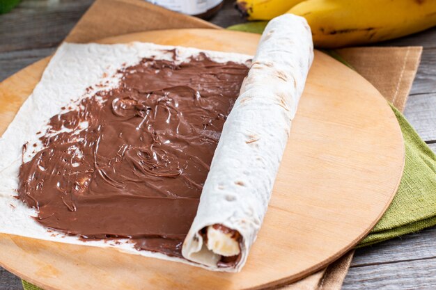 Schritt für Schritt leckere Brötchen mit Bananenscheiben auf Holztisch kochen. Bananenrolle mit Schokoladendessert