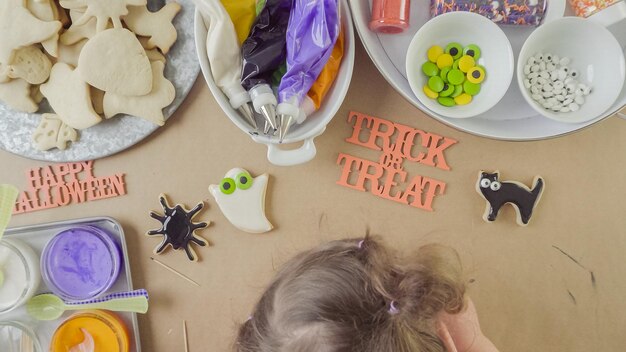 Schritt für Schritt. Mutter und Tochter, die Halloween-Zuckerplätzchen mit bunter königlicher Zuckerglasur verzieren.