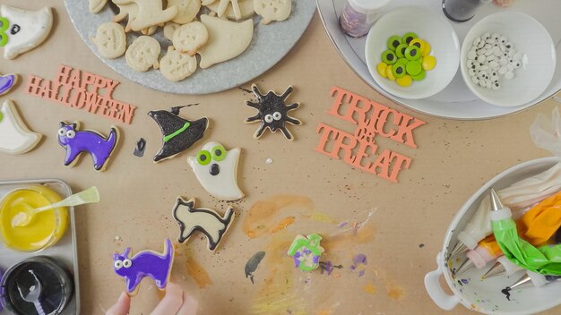 Foto schritt für schritt. mutter und tochter, die halloween-zuckerplätzchen mit bunter königlicher zuckerglasur verzieren.