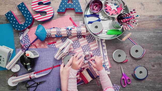 Schritt für Schritt. Mutter und Tochter machen Papierkracher für die Feier am 4. Juli.