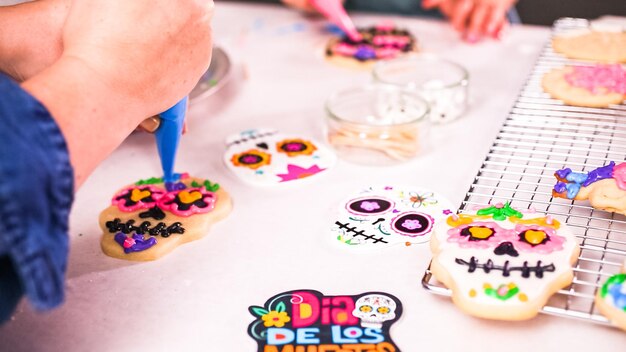 Schritt für Schritt. Mutter und Tochter verzieren Zuckerschädelkekse mit königlicher Zuckerglasur für Dia de los Muertos-Feiertag.