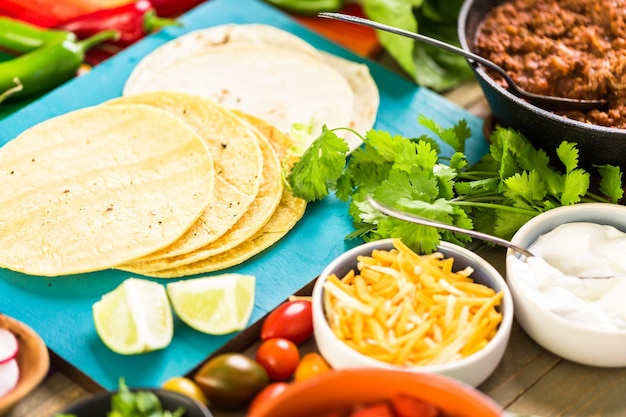Foto schritt für schritt. rinderhack-tacos mit römersalat, tomatenwürfeln, radieschen und geriebenem cheddar-käse.