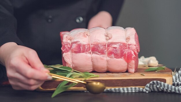 Foto schritt für schritt. roher schweinebraten ohne knochen auf holzschneidebrett mit gewürzen.